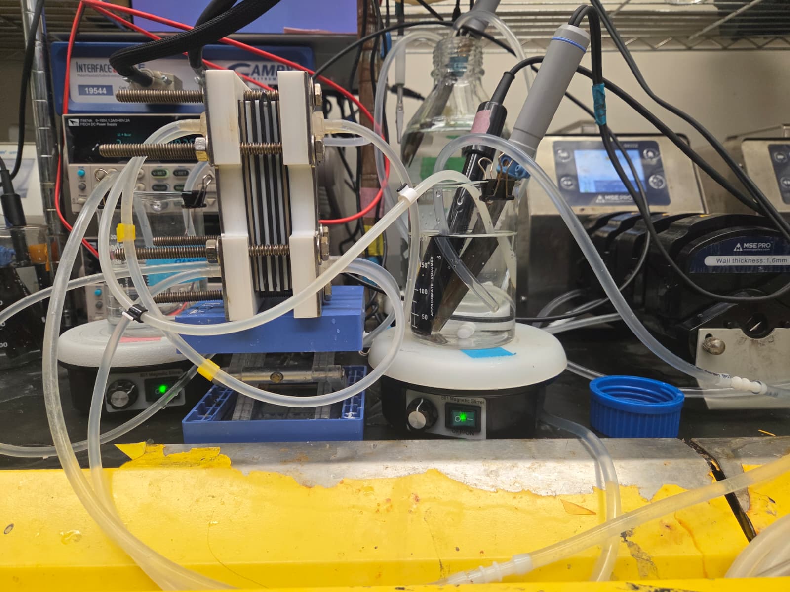 Full bench-scale stacked electrochemical cell test setup with the complete multi-cell stack, fluid connections and measurement instrumentation visible